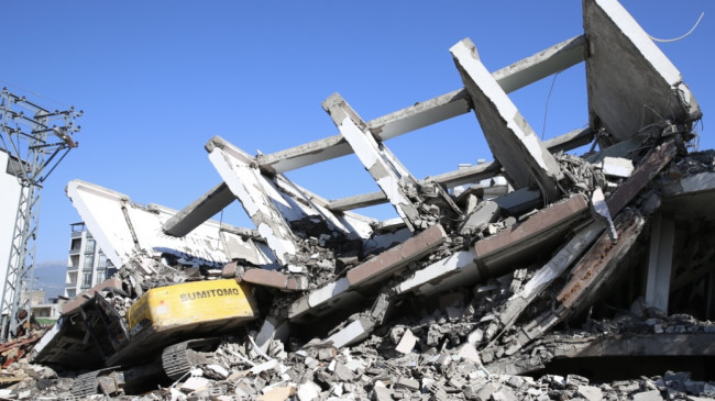 HATAY’DA AĞIR HASARLI BİNA YIKIM SIRASINDA İŞ MAKİNESİNİN ÜZERİNE ÇÖKTÜ! OPERATÖR YARALANDI…